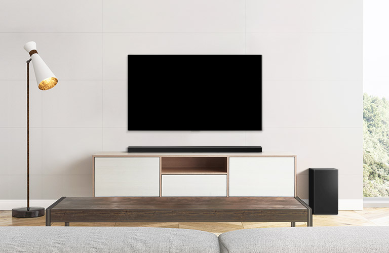 Ein TV, eine Soundbar und ein Subwoofer in einem schlicht eingerichteten Wohnzimmer.