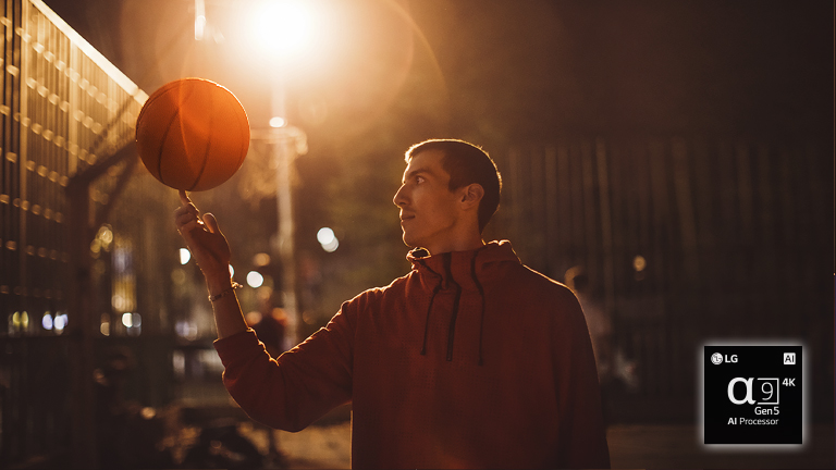 Ein Mann auf einem nächtlichen Basketballplatz lässt einen Basketball auf seinem Finger kreisen