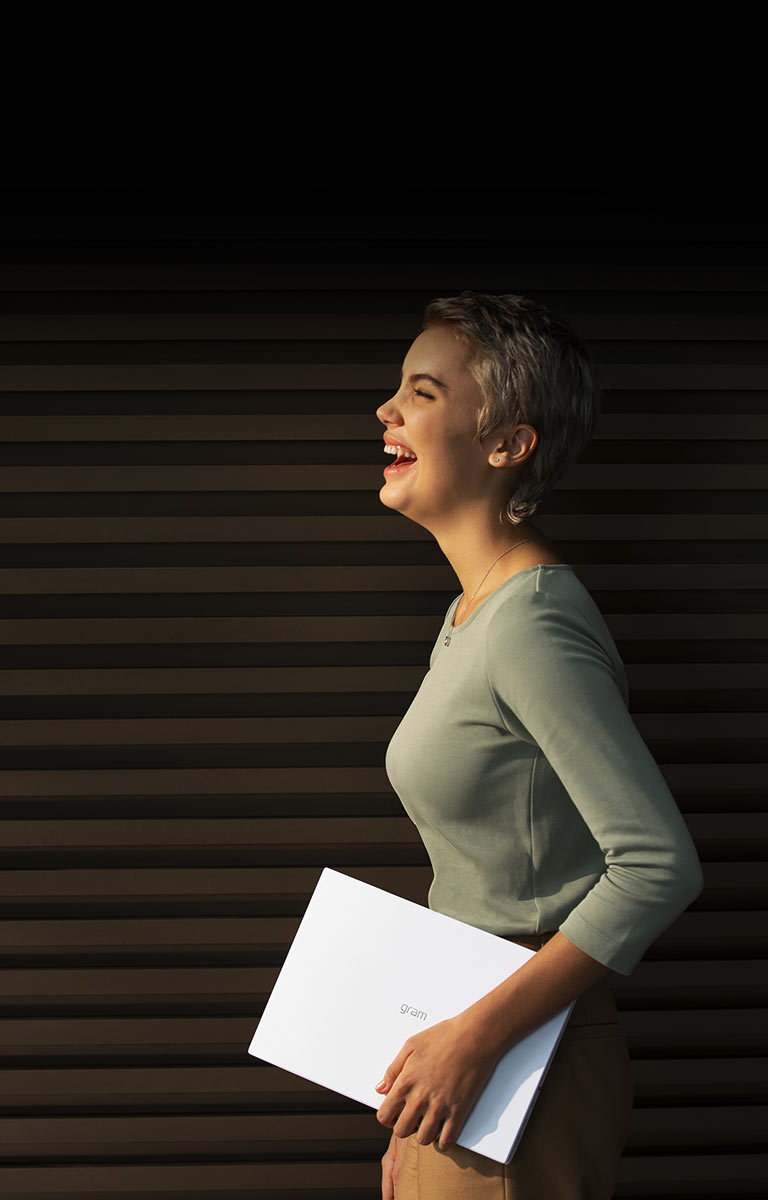 A woman is holding LG gram with big smile.