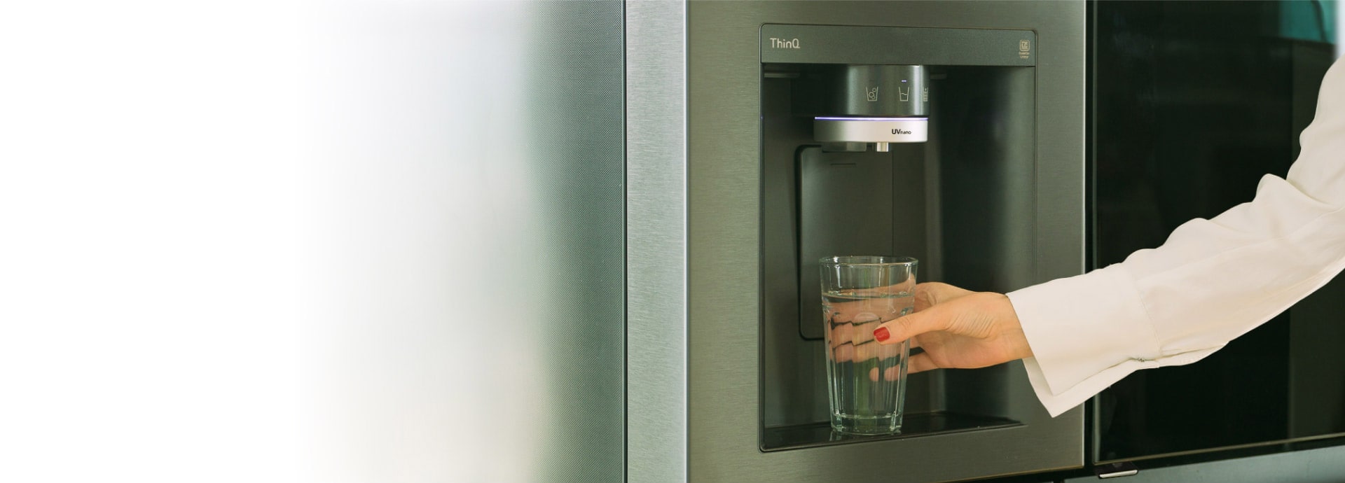 Eine Frau holt sich eine Tasse Wasser aus dem Wasserspender des LG InstaView Side-by-Side Kühlschrankes.