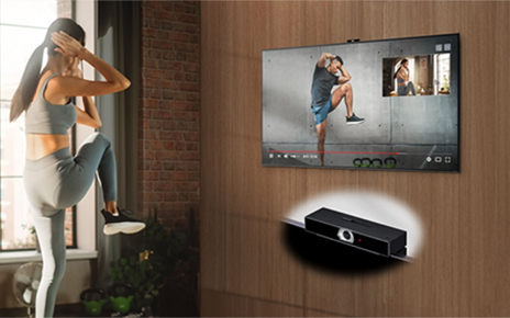 A woman using a fitness application on her LG TV to exercise at home, with LG Smart Cam attached to the top of the TV