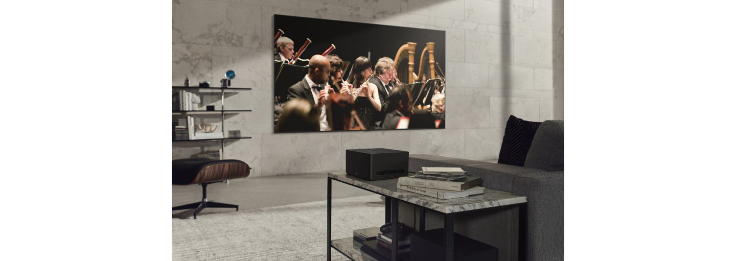 The newly revealed LG SIGNATURE OLED M3 TV mounted on the wall of a gray-themed living room as it displays an orchestra performance