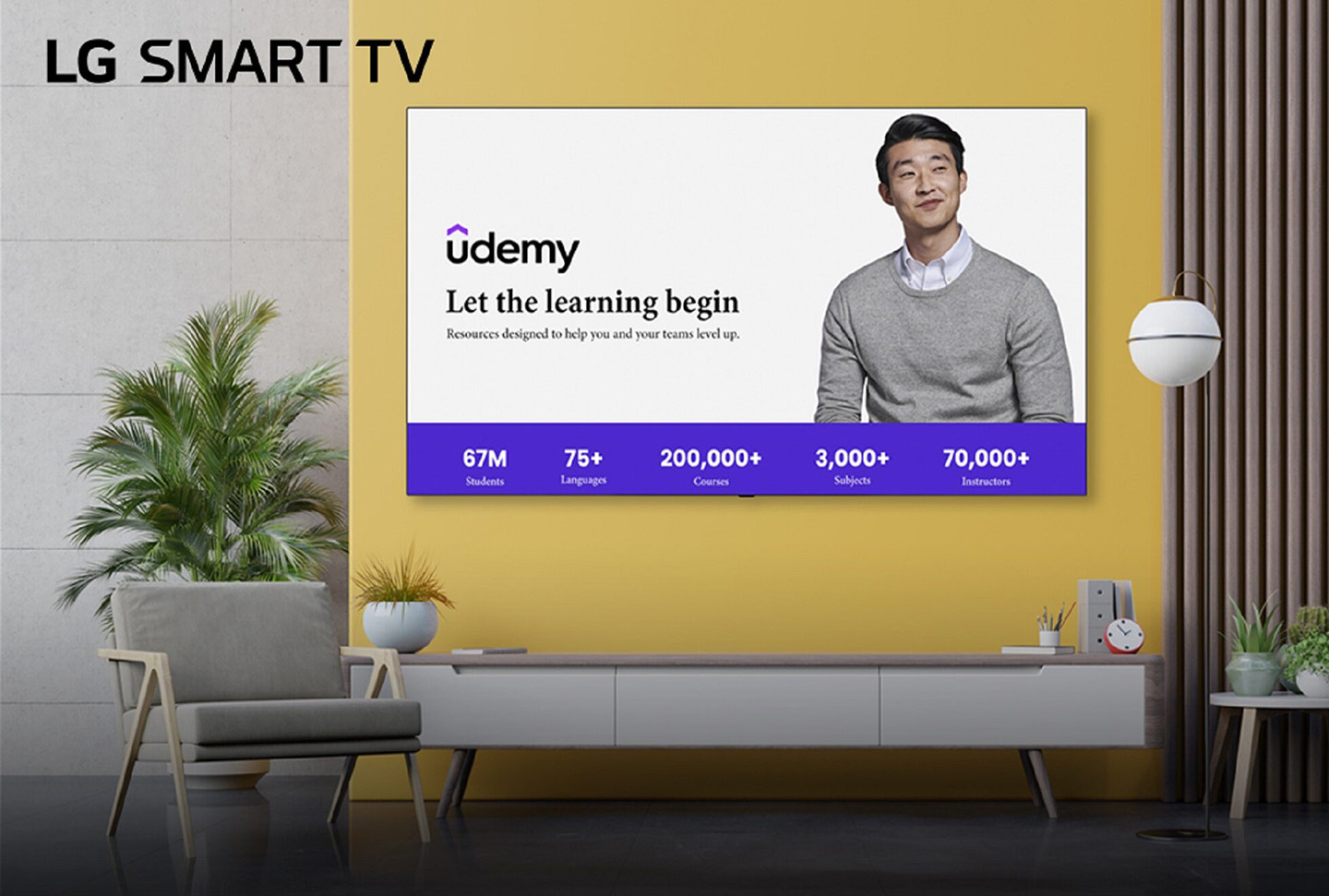 A wall-mounted LG Smart TV displays Udemy’s home screen