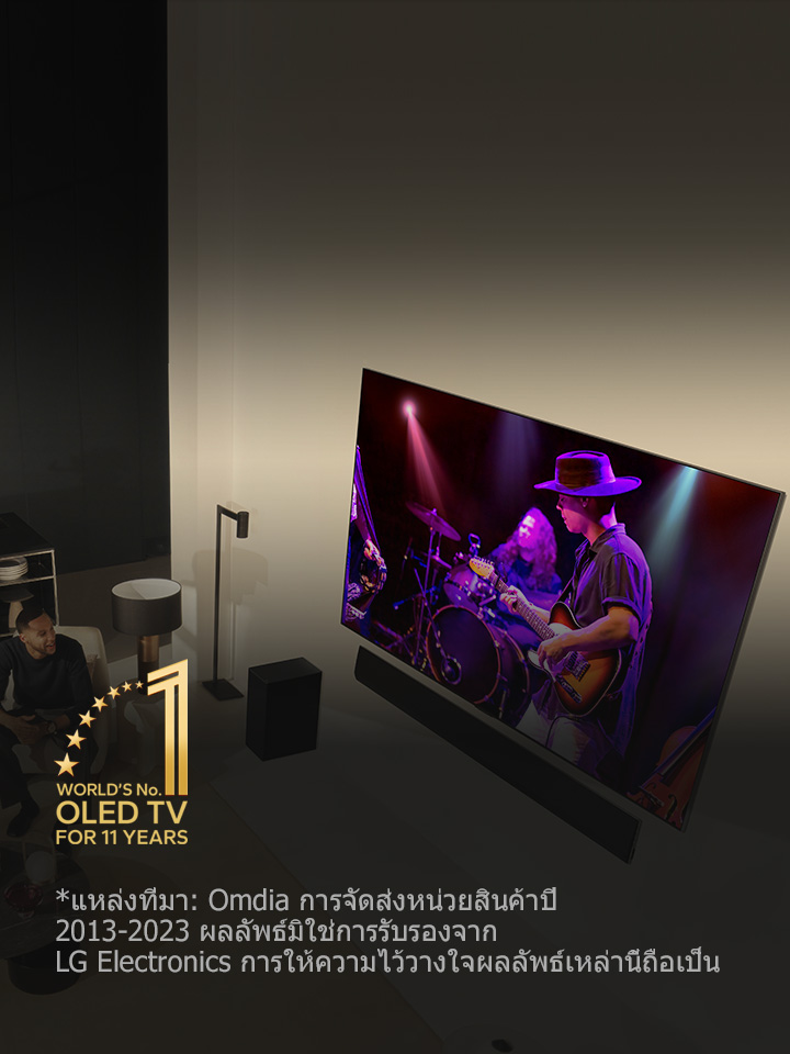 มุมมองเหนือศีรษะของชายและหญิงกำลังดูคอนเสิร์ตบน OLED TV ขนาดใหญ่ในอพาร์ตเมนต์ทันสมัย มีสัญลักษณ์ "OLED TV อันดับ 1 ของโลกเป็นเวลา 11 ปี" ในภาพ ข้อจำกัดความรับผิดชอบระบุว่า: "แหล่งที่มา: Omdia การจัดส่งหน่วยสินค้าปี 2013 ถึง 2023 ผลลัพธ์มิใช่การรับรองจาก LG Electronics การให้ความไว้วางใจผลลัพธ์เหล่านี้ถือเป็นความเสี่ยงของบุคคลภายนอกเอง เข้าชม https://www.omdia.com/ สำหรับรายละเอียดเพิ่มเติม"