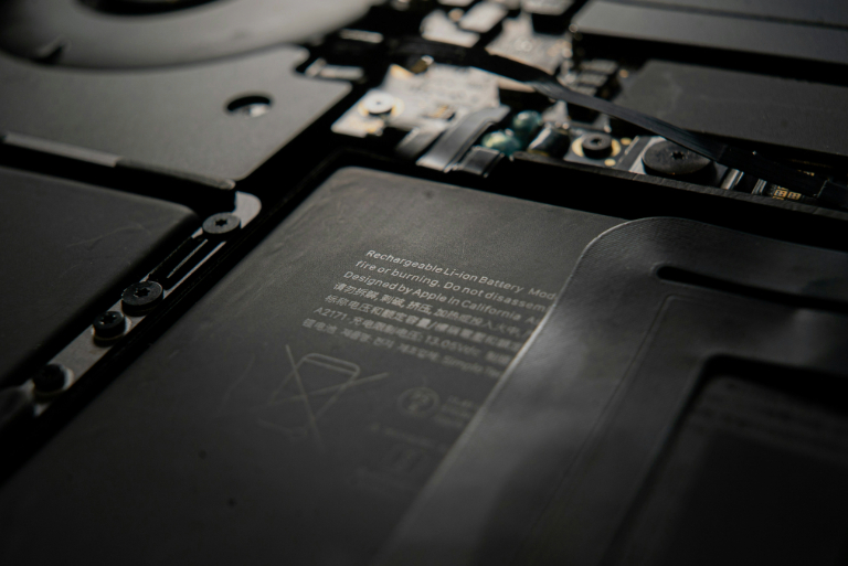 Close-up view of a rechargeable lithium-ion battery inside a laptop, emphasizing text warnings and disposal icons