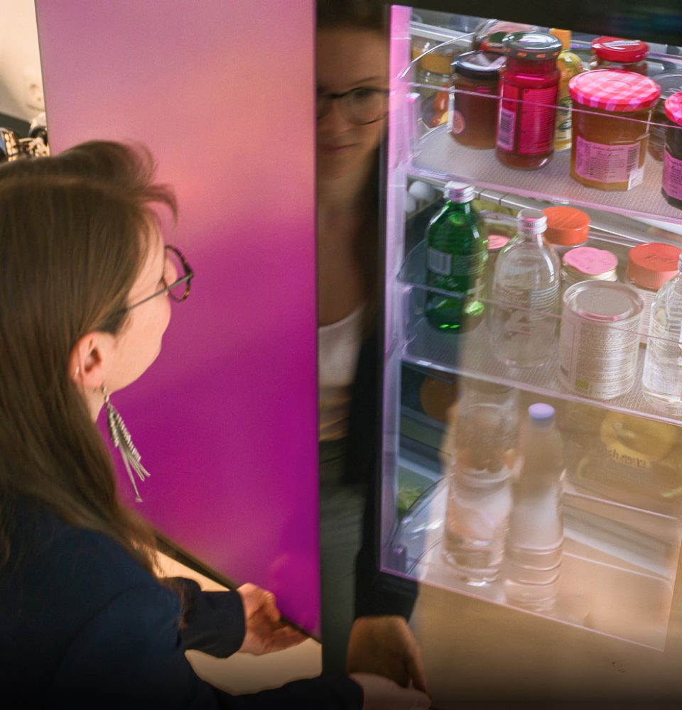 A woman opens the upper door of the LG MoodUP Refrigerator’s mirror glass.