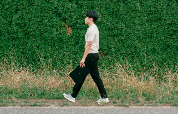 A man walking outdoors while holding LG gram Pro