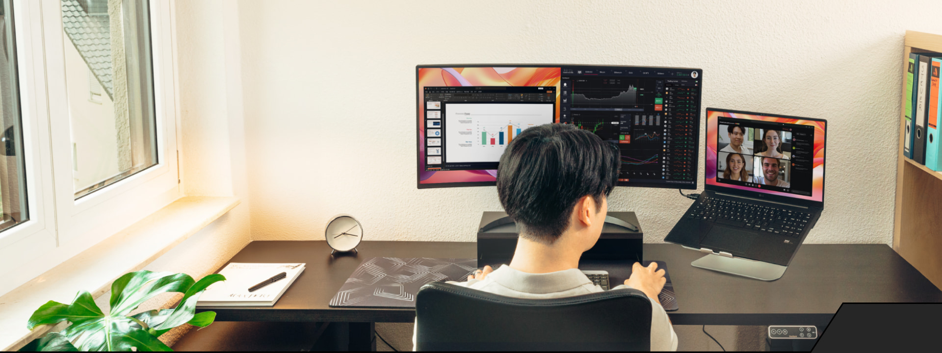 Person working remotely at a dual monitor setup desk, with LG monitor and a laptop showing a video meeting