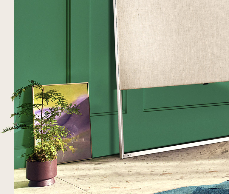 Close-up of EASEL on the floor leaning against the wall together with a painting and decorative plant.