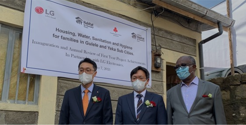 Three men wearing masks stand in front of Ethiopia's veterans' villages, wearing suits and supporting LG's remodeling.