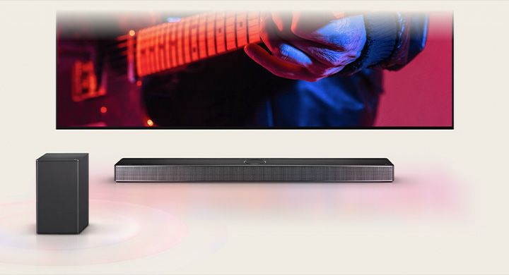 LG TV แสดงภาพผู้ชายกำลังเล่นกีตาร์และมี LG Soundbar อยู่ข้างใต้ โดยมีลำโพงอีกตัวอยู่ด้านหน้า